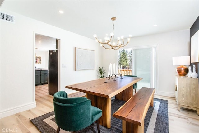 dining area featuring light hardwood / wood-style floors and an inviting chandelier