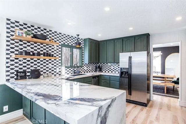 kitchen featuring kitchen peninsula, light wood-type flooring, stainless steel appliances, sink, and green cabinets