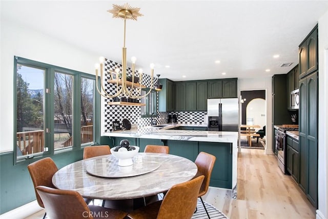 kitchen with kitchen peninsula, stainless steel appliances, plenty of natural light, and light hardwood / wood-style floors