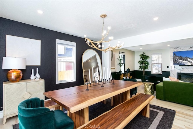 dining area featuring a high end fireplace, light hardwood / wood-style floors, a wealth of natural light, and a notable chandelier