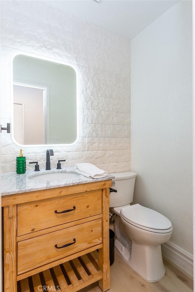 bathroom with hardwood / wood-style floors, vanity, toilet, and tile walls