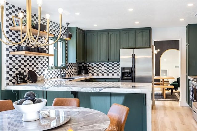 kitchen featuring kitchen peninsula, sink, green cabinetry, stainless steel fridge with ice dispenser, and light hardwood / wood-style floors