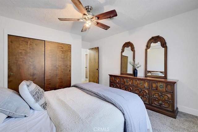 bedroom with ceiling fan, a closet, light colored carpet, and a textured ceiling