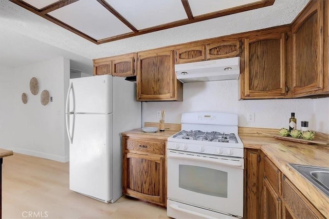 kitchen with butcher block counters, sink, white appliances, and a textured ceiling