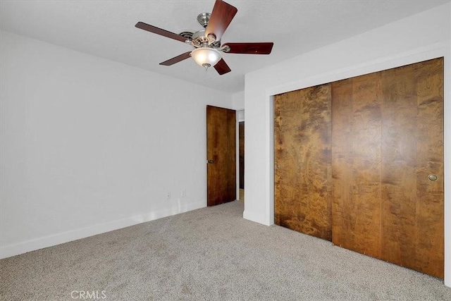 unfurnished bedroom featuring carpet flooring, ceiling fan, and a closet