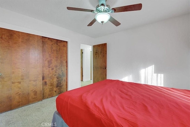 carpeted bedroom featuring ceiling fan and a closet