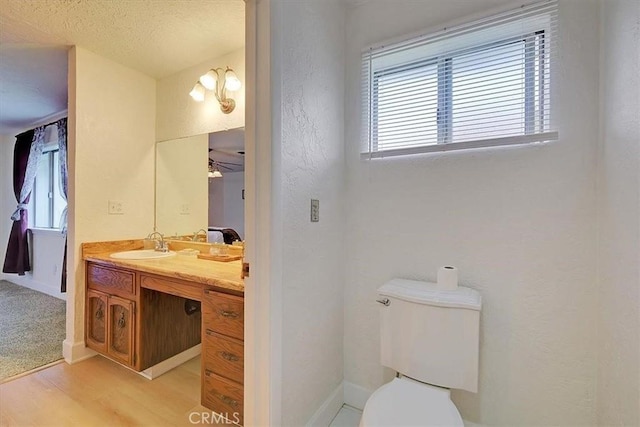 bathroom featuring hardwood / wood-style floors, vanity, ceiling fan, toilet, and a textured ceiling