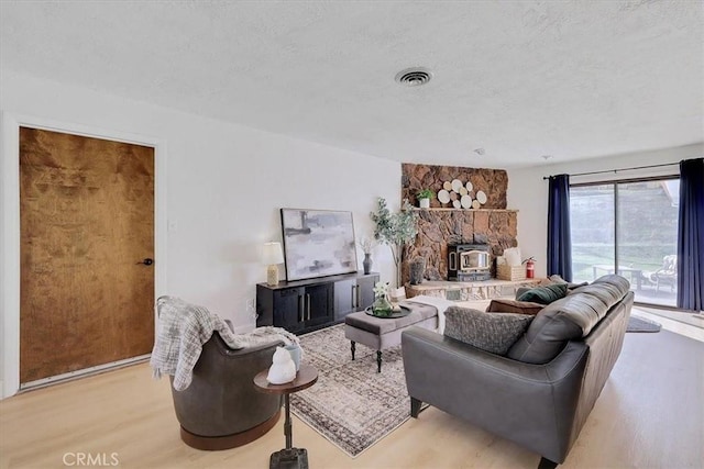 living room with light wood-type flooring, a textured ceiling, and a wood stove