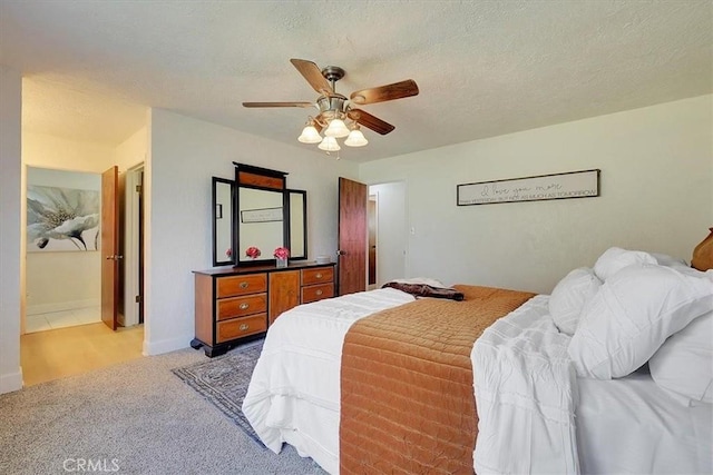 bedroom with a textured ceiling, ceiling fan, and light carpet