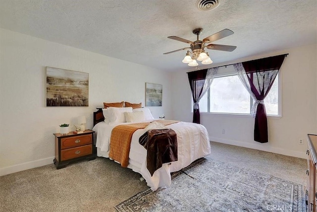 carpeted bedroom featuring ceiling fan and a textured ceiling