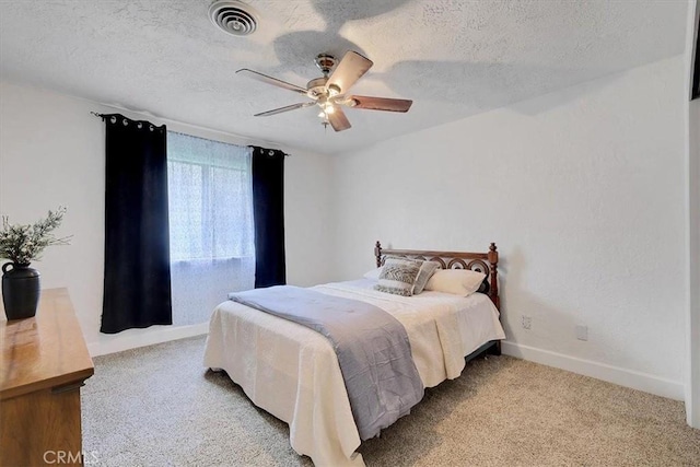 bedroom featuring ceiling fan, light colored carpet, and a textured ceiling