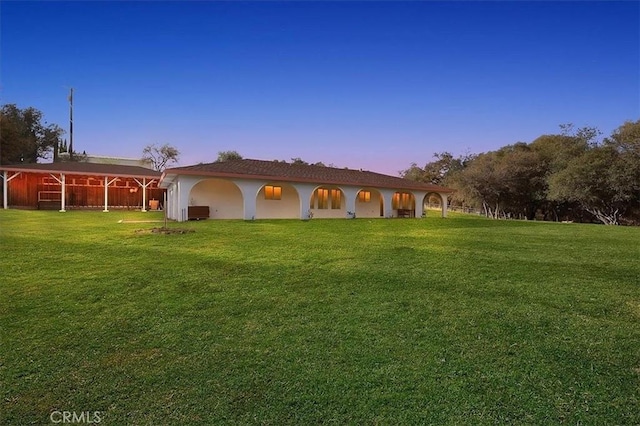 back house at dusk with a lawn