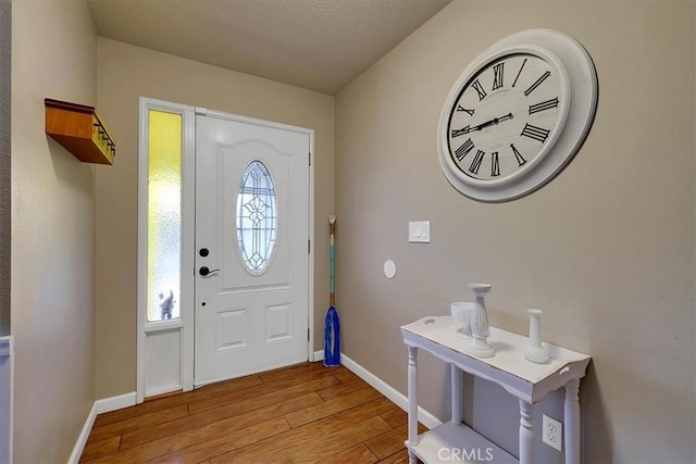 entryway with a wealth of natural light, a textured ceiling, and light wood-type flooring