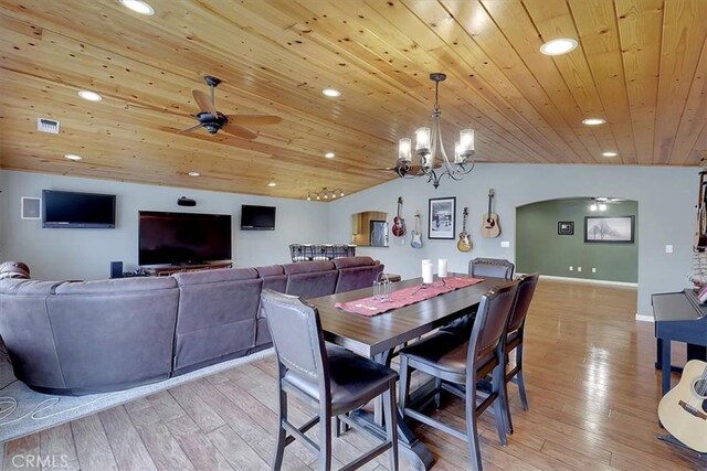 dining space featuring light wood finished floors, ceiling fan, arched walkways, and vaulted ceiling