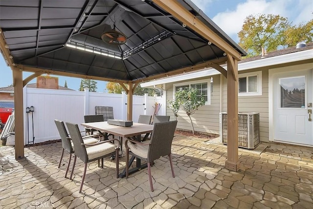 view of patio / terrace with outdoor dining space, fence, a gazebo, and central air condition unit