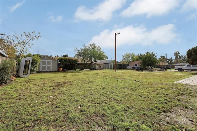 view of yard featuring a storage shed, an outbuilding, and fence