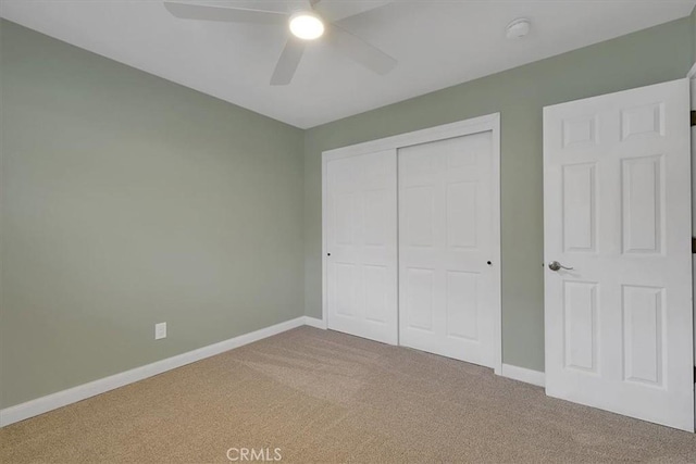 unfurnished bedroom with ceiling fan, a closet, carpet, and baseboards