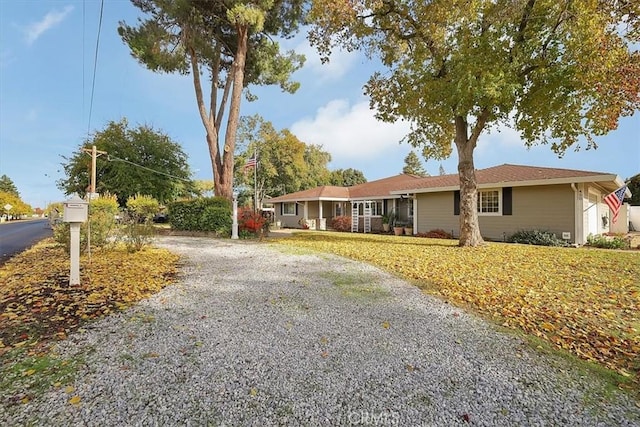 single story home with gravel driveway and a front yard