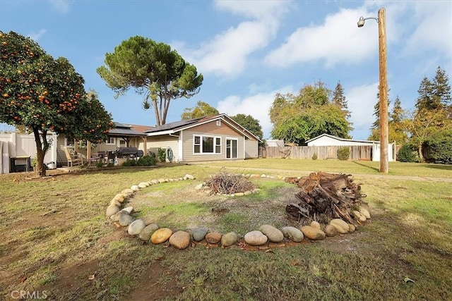 exterior space featuring a patio area, roof mounted solar panels, fence, and a lawn