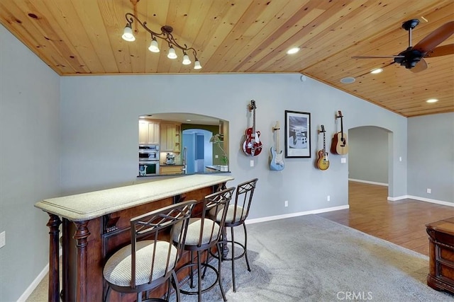 kitchen with arched walkways, wood ceiling, baseboards, vaulted ceiling, and dark colored carpet