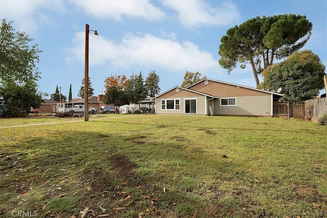 rear view of house with a yard and fence