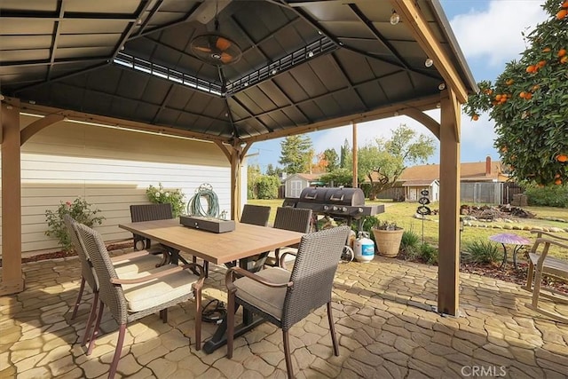 view of patio with an outbuilding, fence, a storage unit, a gazebo, and outdoor dining space