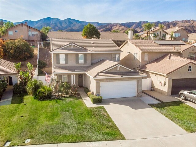 view of front of home with a mountain view, a front yard, and a garage