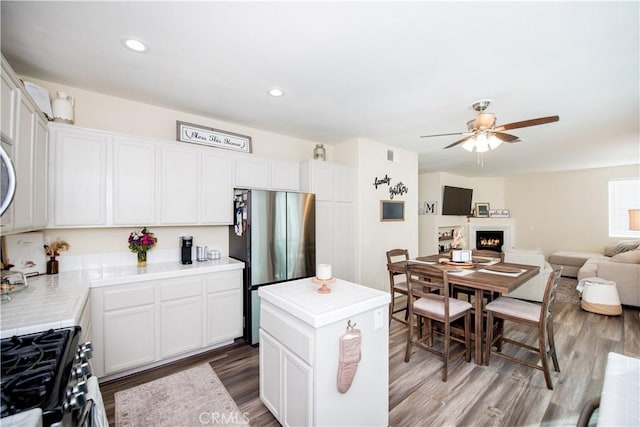 kitchen featuring white cabinets, wood-type flooring, a center island, and stainless steel appliances