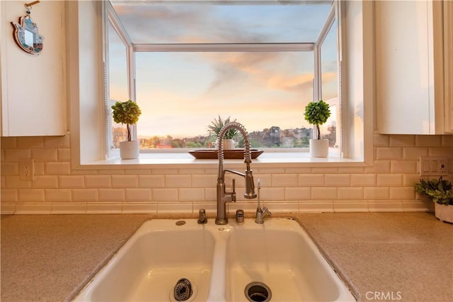 interior details featuring white cabinetry, decorative backsplash, and sink