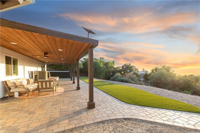 patio terrace at dusk with outdoor lounge area and ceiling fan