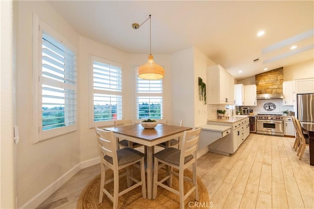 kitchen featuring high end stove, white cabinetry, light hardwood / wood-style floors, and vaulted ceiling