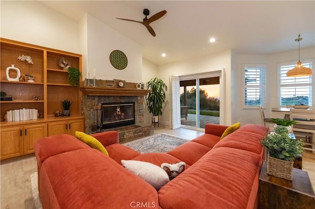 living room with ceiling fan, lofted ceiling, a fireplace, and light hardwood / wood-style flooring