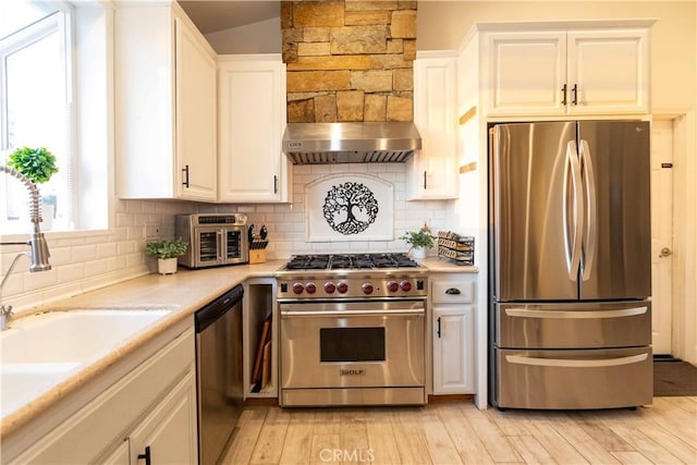 kitchen with white cabinets, stainless steel appliances, light hardwood / wood-style floors, and range hood