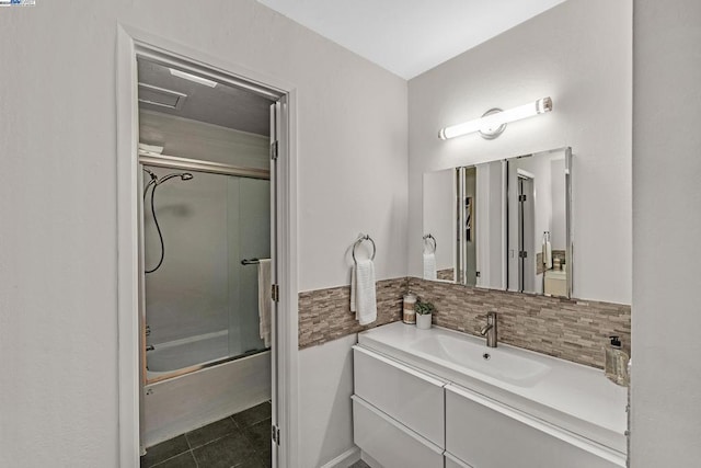 bathroom featuring tile patterned flooring, vanity, bath / shower combo with glass door, and tasteful backsplash