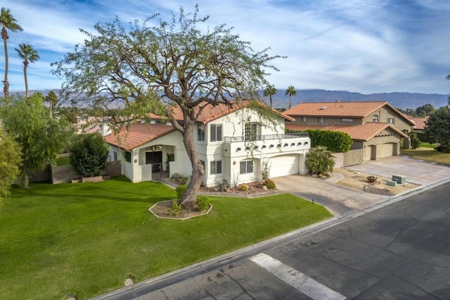 mediterranean / spanish-style home featuring a mountain view, a balcony, a front yard, and a garage