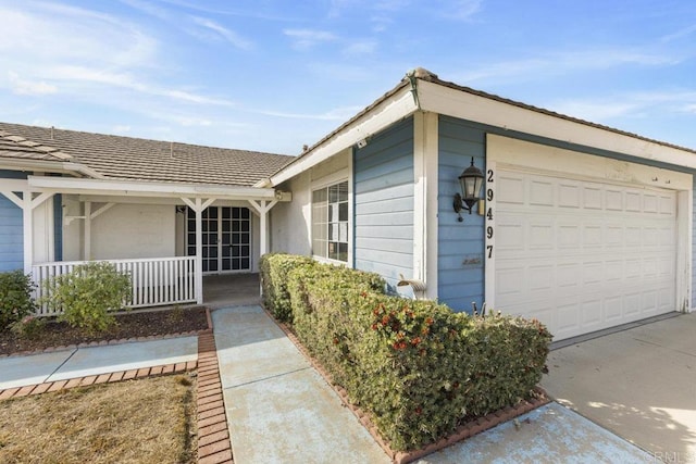 view of exterior entry featuring covered porch and a garage