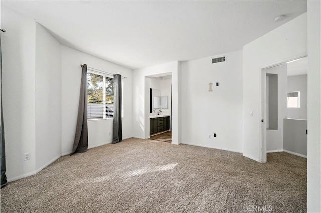 unfurnished bedroom featuring carpet floors, sink, and ensuite bathroom