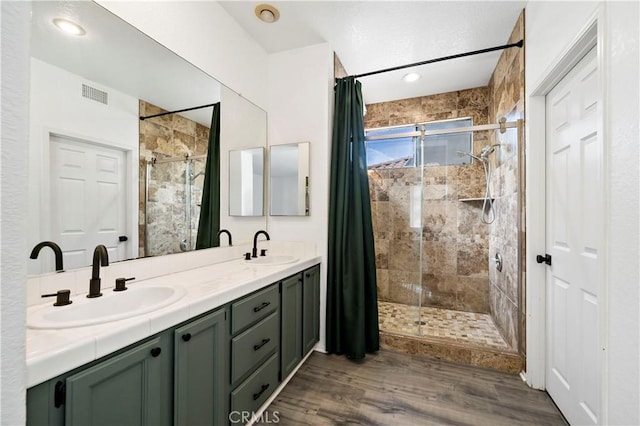 bathroom with a tile shower, hardwood / wood-style flooring, and vanity