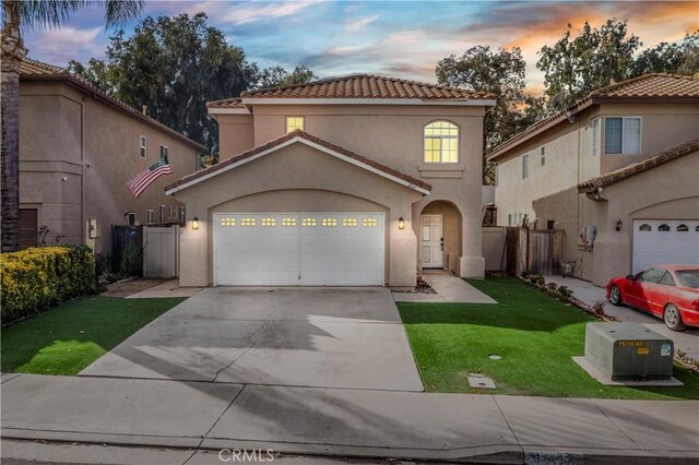 mediterranean / spanish home with a garage and a yard