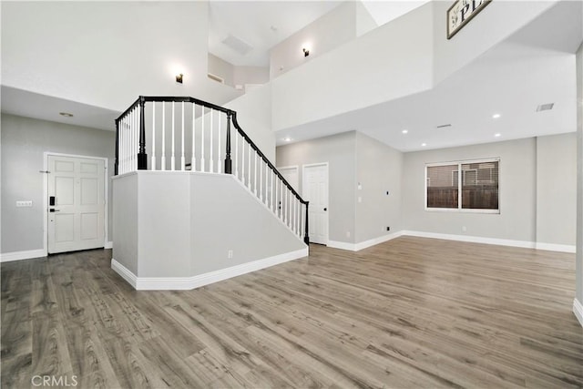 unfurnished living room featuring a towering ceiling and hardwood / wood-style flooring