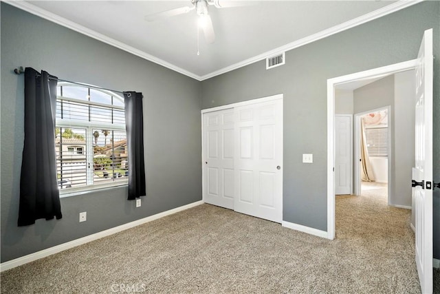 unfurnished bedroom featuring ceiling fan, light colored carpet, a closet, and crown molding