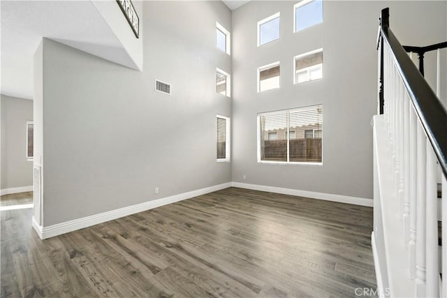 unfurnished living room featuring dark hardwood / wood-style flooring and a towering ceiling