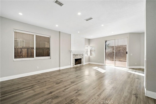 unfurnished living room featuring hardwood / wood-style flooring and a stone fireplace