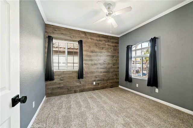 carpeted spare room featuring ceiling fan, crown molding, and wood walls