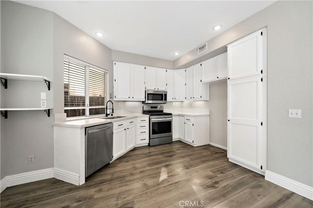 kitchen featuring dark wood-type flooring, appliances with stainless steel finishes, white cabinetry, and sink