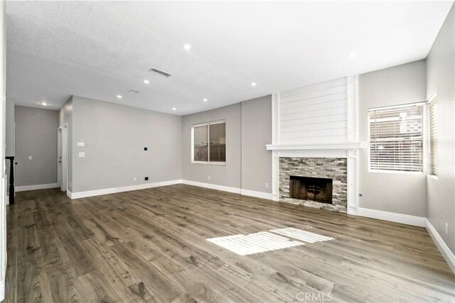 unfurnished living room featuring wood-type flooring and a stone fireplace