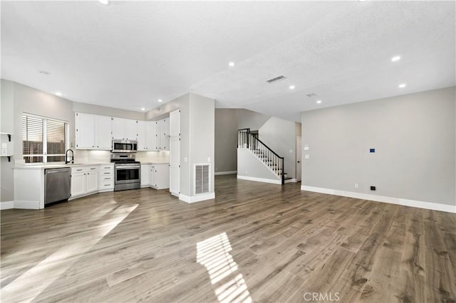 kitchen with light hardwood / wood-style flooring, sink, stainless steel appliances, and white cabinetry