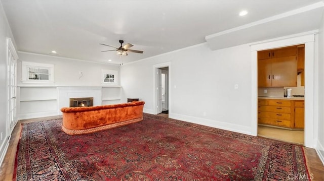 living room featuring hardwood / wood-style flooring, ceiling fan, and crown molding