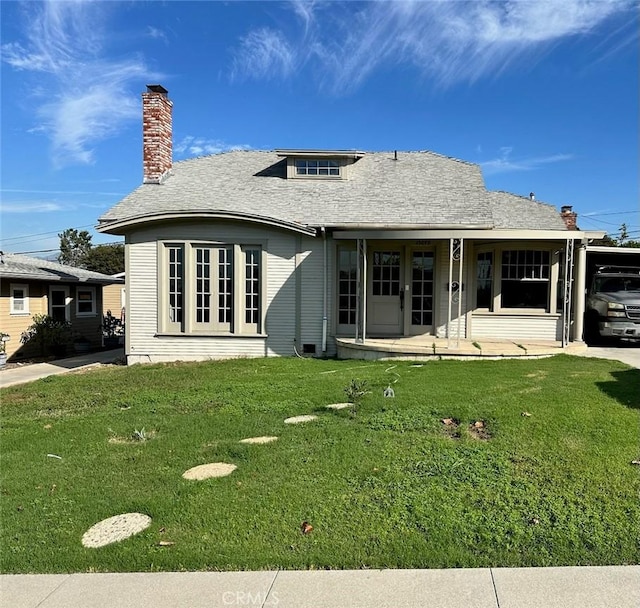 rear view of property featuring a lawn and a carport