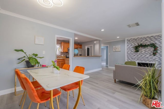 dining room with ornamental molding and light wood-type flooring